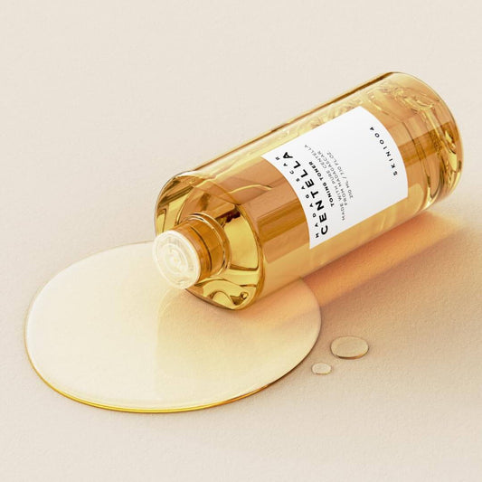 SKIN1004 Madagascar Centella Toning Toner in a bottle with a smooth liquid spill, suitable for gentle daily skin care.