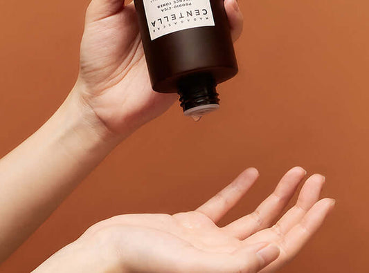 Skin1004 Madagascar Centella Probio-Cica Essence Toner being poured into a palm for skincare application.