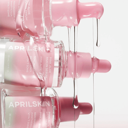 APRILSKIN Pink Aloe Mucin Serum bottles with pink liquid dripping, showcasing hydration and revitalization for skin.