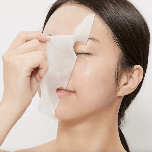 Woman applying VT Cica Collagen Mask to her face, showcasing skincare routine for youthful skin.