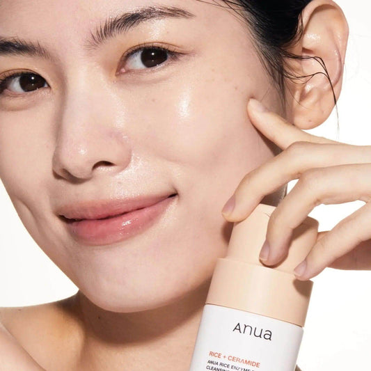 Close-up of a woman showcasing Anua Rice Enzyme Brightening Cleansing Powder for radiant, healthy skin.