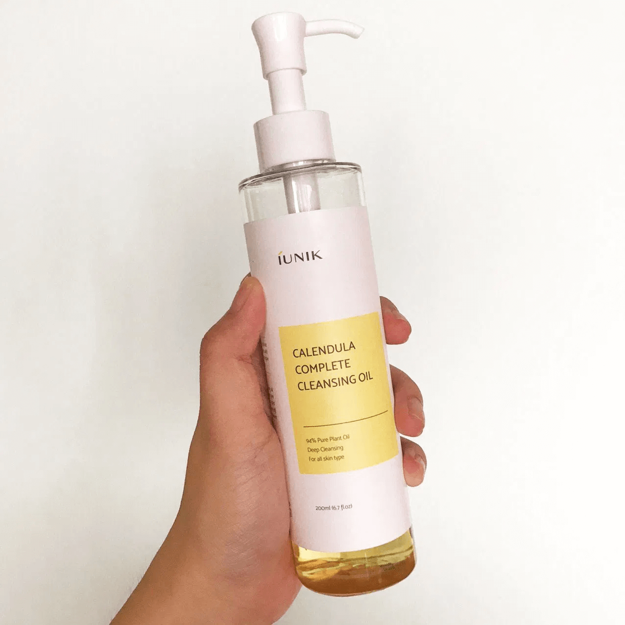 iUNIK Calendula Complete Cleansing Oil 200ml in hand, effective gentle cleanser for sensitive skin, removes makeup and impurities.