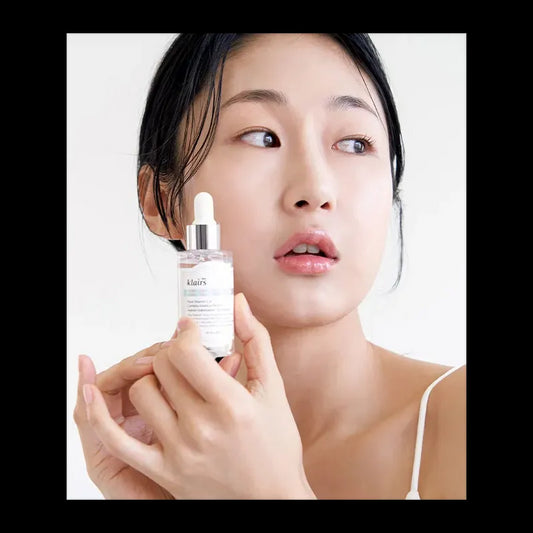 Dear, Klairs Freshly Juiced Vitamin Drop serum being held by a model, showcasing its anti-aging benefits.