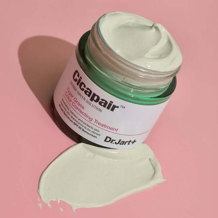 Dr.Jart+ Cicapair Tiger Grass Color Correcting Treatment jar with product spilling on a pink background