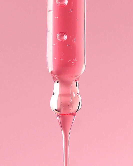 Close-up of pink ANUA Niacinamide 10% + TXA 4% Serum in a dropper against a soft pink background.