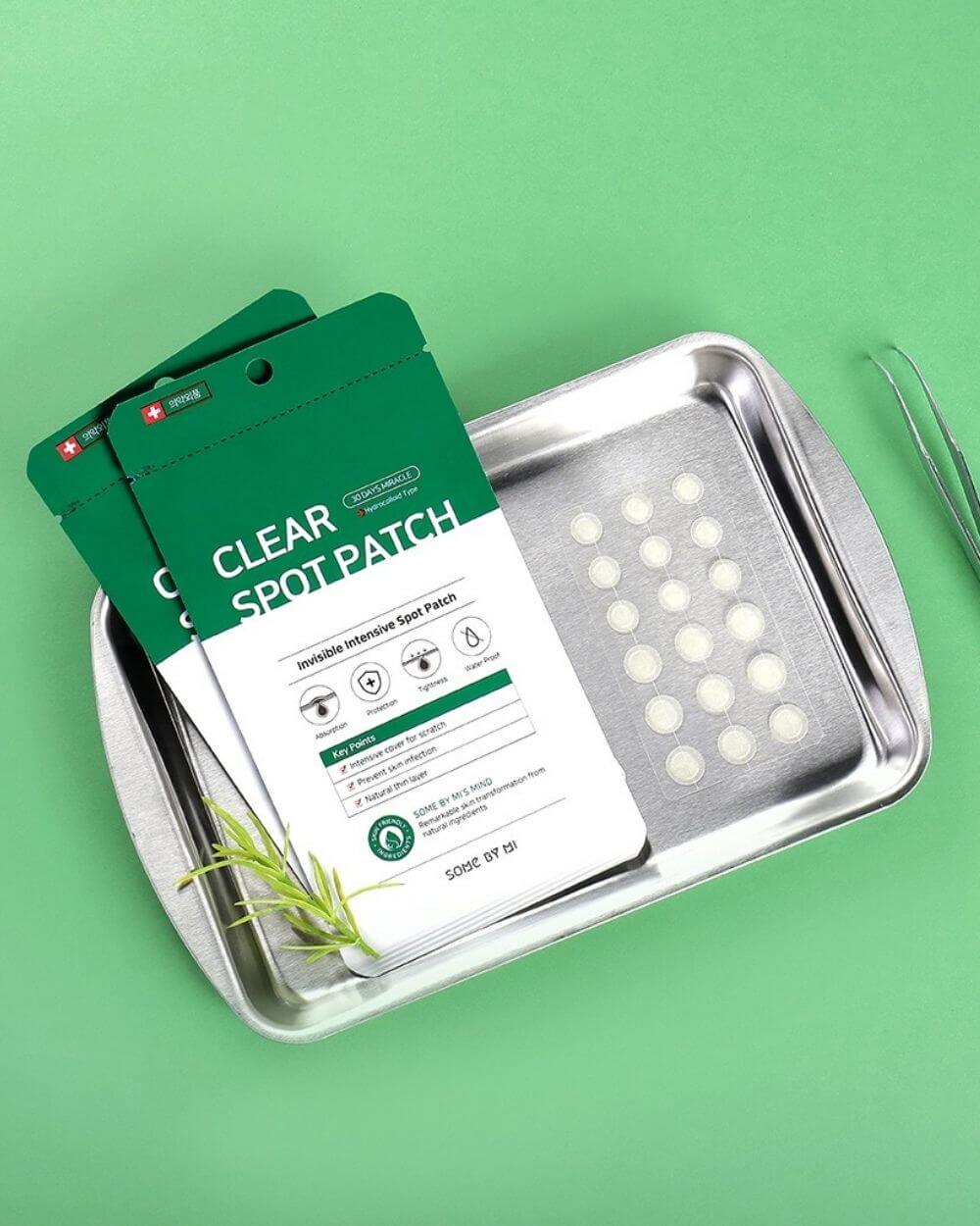 Some By Mi Clear Spot Patch packaging displayed on a stainless steel tray with a green background, highlighting acne treatment solution.