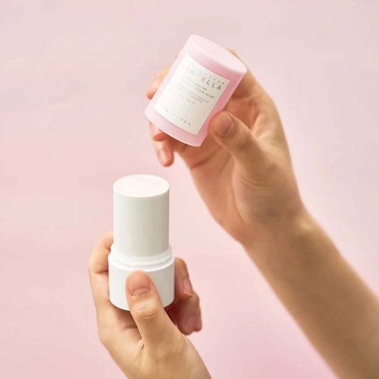 Hands holding Skin1004 Madagascar Centella Poremizing Quick Clay Stick Mask with pink packaging.