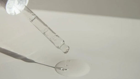 Dropper dispensing clear serum on a surface, showcasing a key skincare ingredient for glowing skin.